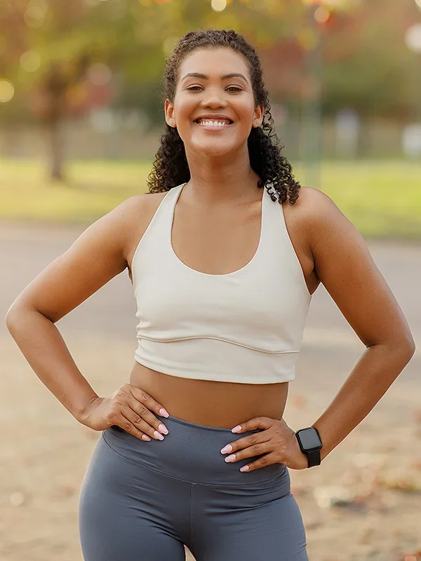 young woman with hands on hips wearing running clothes looking at camera confidently